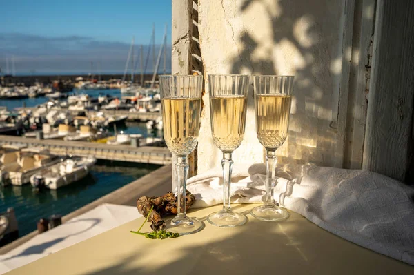 Üç bardak Fransız şampanyası köpüklü şarap ve renkli balıkçı teknelerinin manzarası Cassis, Provence, Fransa 'daki eski limanda, yaz partisinde