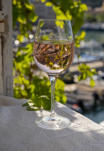 Açık terasta sunulan Rose Provencal şarabı Cassis, Provence, Fransa 'daki eski balıkçıların limanında renkli teknelerle servis ediliyor.
