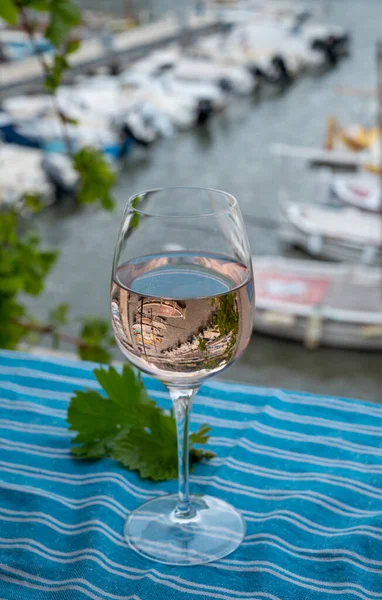 Açık terasta sunulan Rose Provencal şarabı Cassis, Provence, Fransa 'daki eski balıkçıların limanında renkli teknelerle servis ediliyor.