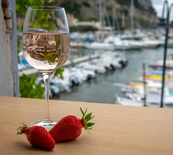 Açık terasta sunulan Rose Provencal şarabı Cassis, Provence, Fransa 'daki eski balıkçıların limanında renkli teknelerle servis ediliyor.