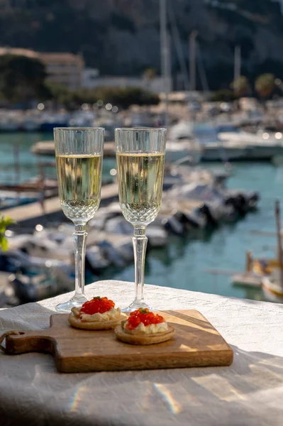 Ekşi krema ve tuzlu somon kırmızısı havyar ve Fransız şampanyası brut köpüklü şarap ile küçük krep çiftleri Cassis, Provence, Fransa 'nın limanındaki renkli teknelerde servis edilir.