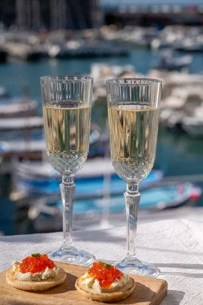 Ekşi krema ve tuzlu somon kırmızısı havyar ve Fransız şampanyası brut köpüklü şarap ile küçük krep çiftleri Cassis, Provence, Fransa 'nın limanındaki renkli teknelerde servis edilir.