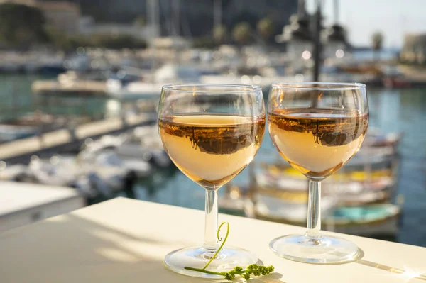 Soğuk gül ve cam içinde Provencal şarabı olan yaz partisi açık terasta güneş ışığında eski balıkçıların limanı manzaralı Cassis, Provence, Fransa 'da renkli teknelerle servis edilir.