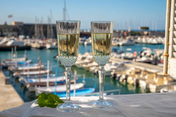 İki bardak Fransız şampanyası, köpüklü şarap ve renkli balıkçı teknesiyle Cassis, Provence, Fransa 'daki eski limanda öğle yemeği.