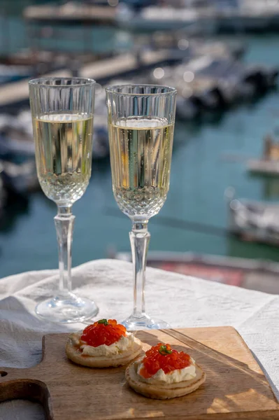 Ekşi krema ve tuzlu somon kırmızısı havyar ve Fransız şampanyası brut köpüklü şarap ile küçük krep çiftleri Cassis, Provence, Fransa 'nın limanındaki renkli teknelerde servis edilir.