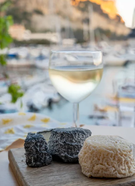 Fransız beyaz ve siyah keçi peyniri crottin ve bir bardak beyaz Fransız şarabı Cassis, Provence, Fransa limanındaki teknelerde servis edilir.
