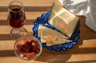 İspanyol sert manchegosu, inek, koyun ve keçi peyniri açık havada membrillo reçeli ve bir bardak şeri şarabı ile servis edilir. Mavi Endülüs stil panosunda. Kapatın.