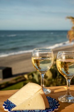 İspanyol sert manchegosu, inek, koyun ve keçi peyniri güneşli bir günde açık havada beyaz şarap ve mavi deniz manzarasıyla servis edilir.