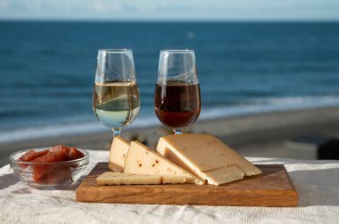 İspanyol sert Endülüs peyniri tatlı şeri ile dolu açık havada servis edilen membrillo reçeli ve iki bardak şeri şarabı ile arka planda plaj ve mavi deniz, kapatın.