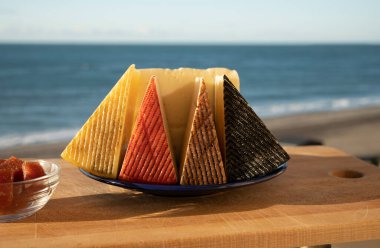 İspanyol sert peynirleri, curado, manchego, keçi peyniri arka planda mavi denizli membrillo reçeli servis edilir.