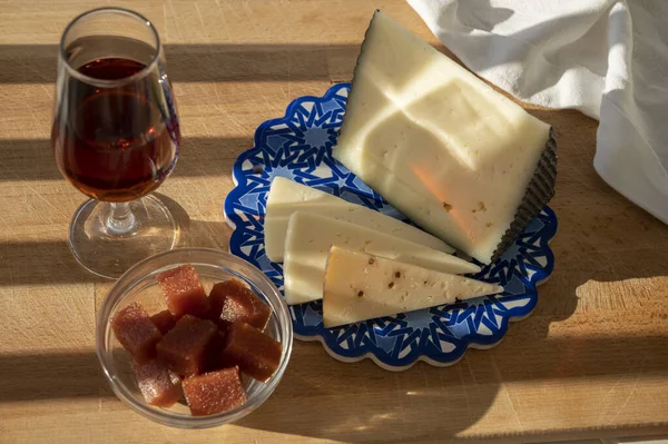 İspanyol sert manchegosu, inek, koyun ve keçi peyniri açık havada membrillo reçeli ve bir bardak şeri şarabı ile servis edilir. Mavi Endülüs stil panosunda. Kapatın.