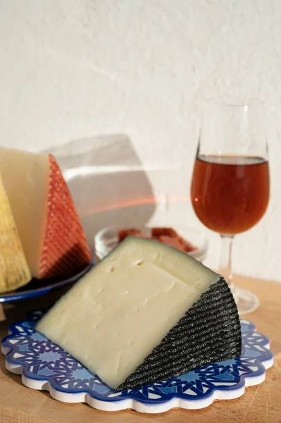 İspanyol sert manchegosu, inek, koyun ve keçi peyniri açık havada membrillo reçeli ve bir bardak şeri şarabı ile servis edilir. Mavi Endülüs stil panosunda. Kapatın.