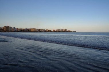 Tenerife Adası, İspanya 'nın güneyindeki El Medano' da kumlu sahilde gün batımında dinleniyorum.