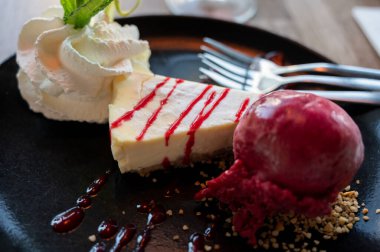 Bir parça peynirli kek, içinde cassis ice, çırpılmış krema ve taze nane şekeri, tatlı tatlılar var.