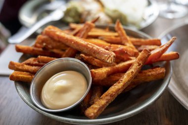 Bowl with tasty deep fried sweet potato chips served with mayonnaise sauce