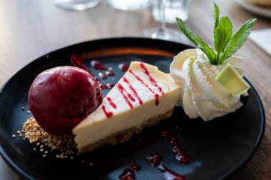 Bir parça peynirli kek, içinde cassis ice, çırpılmış krema ve taze nane şekeri, tatlı tatlılar var.