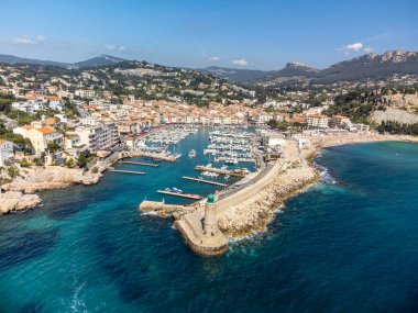 Kumsalda panoramik hava manzarası, mavi deniz, uçurumlar, evler, sokaklar ve Cassis, Provence, Fransa 'da deniz feneri olan eski balıkçıların limanı bulutlu bir günde