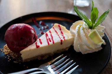 Bir parça peynirli kek, içinde cassis ice, çırpılmış krema ve taze nane şekeri, tatlı tatlılar var.