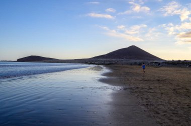 Tenerife Adası, İspanya 'nın güneyindeki El Medano' da kumlu sahilde gün batımında dinleniyorum.