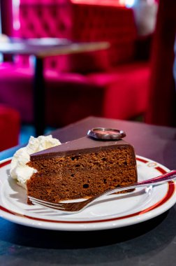 Meşhur Sachertorte çikolatalı pastası. Kayısı reçeli ve beyaz tahtada krem şanti ile servis ediliyor.