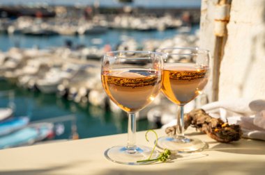Soğuk gül ve cam içinde Provencal şarabı olan yaz partisi açık terasta güneş ışığında eski balıkçıların limanı manzaralı Cassis, Provence, Fransa 'da renkli teknelerle servis edilir.