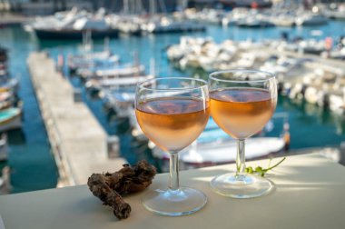 Soğuk gül Provencal şarabı bardaklarla sunuluyor. Açık terasta sunuluyor. Eski balıkçıların limanında, Cassis, Provence, Fransa 'da renkli tekneleri var.