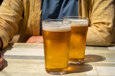 Güneşli yaz gününde Fransız açık hava kafesinde iki bardak taze soğuk bira içen adamlar.