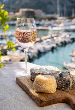 Fransız keçi peyniri crottin ve selles-sur-cher Cassis, Provence, Fransa 'nın limanındaki teknelerde sunuluyor. Peynir, bir bardak kurumuş gül şarabı tadıyor.