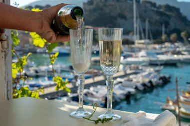 İki bardak Fransız şampanyası, köpüklü şarap ve renkli balıkçıların Cassis, Provence, Fransa 'da eski bir limandaki teknelerine manzarası, Provence' de yaz tatili.
