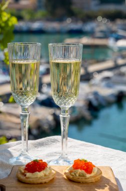 Ekşi krema ve tuzlu somon kırmızısı havyar ve Fransız şampanyası brut köpüklü şarap ile küçük krep çiftleri Cassis, Provence, Fransa 'nın limanındaki renkli teknelerde servis edilir.
