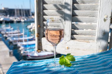 Açık terasta sunulan Rose Provencal şarabı Cassis, Provence, Fransa 'daki eski balıkçıların limanında renkli teknelerle servis ediliyor.