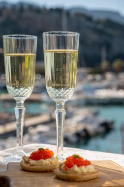 Ekşi krema ve tuzlu somon kırmızısı havyar ve Fransız şampanyası brut köpüklü şarap ile küçük krep çiftleri Cassis, Provence, Fransa 'nın limanındaki renkli teknelerde servis edilir.
