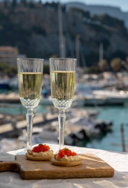Ekşi krema ve tuzlu somon kırmızısı havyar ve Fransız şampanyası brut köpüklü şarap ile küçük krep çiftleri Cassis, Provence, Fransa 'nın limanındaki renkli teknelerde servis edilir.