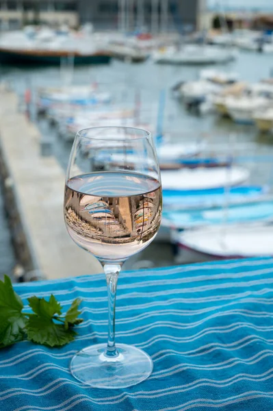 Açık terasta sunulan Rose Provencal şarabı Cassis, Provence, Fransa 'daki eski balıkçıların limanında renkli teknelerle servis ediliyor.