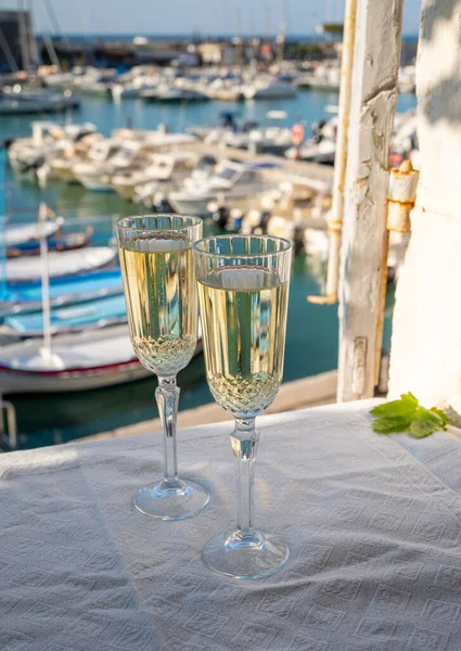 Birthday celebration in summer with two glasses of French champagne sparkling wine and view on colorful fisherman\'s boats in old harbour in Cassis, Provence, France