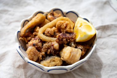 İspanyol deniz ürünleri, kızarmış bebek ahtapot, balık, limonla servis edilen kalamar halkaları, yakın çekim.