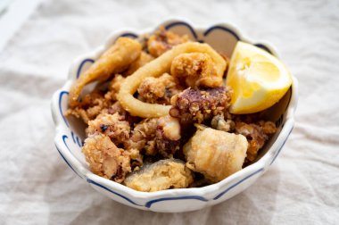 İspanyol deniz ürünleri, kızarmış bebek ahtapot, balık, limonla servis edilen kalamar halkaları, yakın çekim.