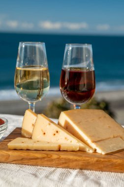 İspanyol sert Endülüs peyniri tatlı şeri ile dolu açık havada servis edilen membrillo reçeli ve iki bardak şeri şarabı ile arka planda plaj ve mavi deniz, kapatın.