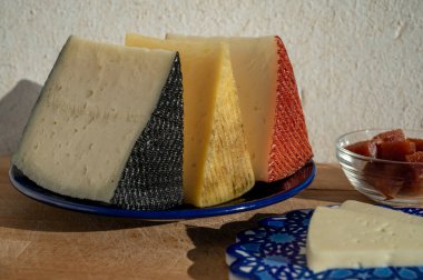 İspanyol sert manchegosu, inek, koyun ve keçi peyniri açık havada, mavi Endülüs stili tahtasında güneş ışığında membrillo reçeli servis edilir.