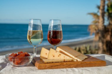 İspanyol sert Endülüs peyniri tatlı şeri ile dolu açık havada servis edilen membrillo reçeli ve iki bardak şeri şarabı ile arka planda plaj ve mavi deniz, kapatın.