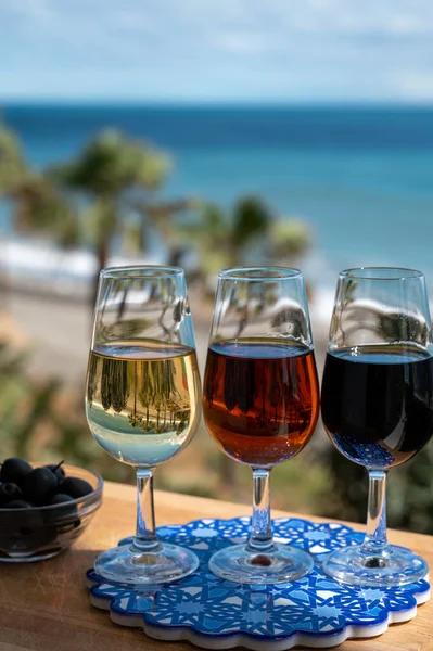 Tasting of Spanish sweet and dry fortified Vino de Jerez sherry wine and green olives with view on blue sea and beach near El Puerto de Santa Maria, Andalusia, Spain