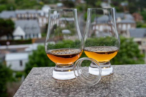 Two drams of scotch whiskey with view on old houses on background, Edinburgh whisky tasting tour, Scotland