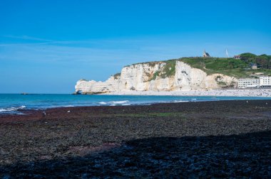 Alçak gelgit dönemi ve okyanusun dibindeki beyaz taşların manzarası ve Fransa 'nın Normandiya eyaletindeki Porte d' Aval kemerinin tebeşir kayalıkları. Turistler için tatil yeri.