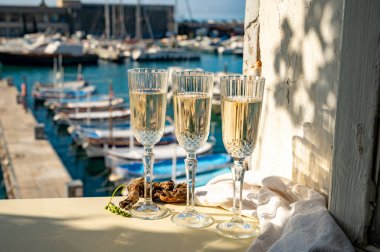 Üç bardak Fransız şampanyası köpüklü şarap ve renkli balıkçı teknelerinin manzarası Cassis, Provence, Fransa 'daki eski limanda, yaz partisinde
