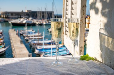 Yazın doğum günü kutlaması iki bardak Fransız şampanyası köpüklü şarap ve renkli balıkçı tekneleriyle Cassis, Provence, Fransa 'daki eski limanda.