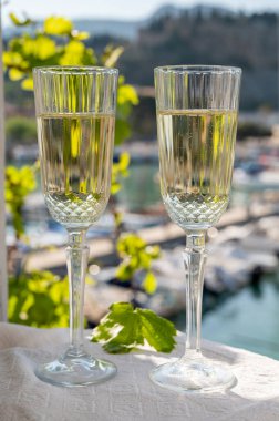 İki bardak Fransız şampanyası, köpüklü şarap ve renkli balıkçı teknesiyle Cassis, Provence, Fransa 'daki eski limanda öğle yemeği.