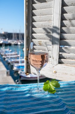 Açık terasta sunulan Rose Provencal şarabı Cassis, Provence, Fransa 'daki eski balıkçıların limanında renkli teknelerle servis ediliyor.