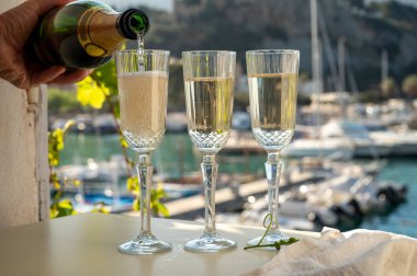 Üç bardak Fransız şampanyası, köpüklü şarap ve renkli balıkçıların Cassis, Provence, Fransa 'daki eski limanlarında bulunan teknelerine manzaralı bir manzara, Provence' de yaz tatili.