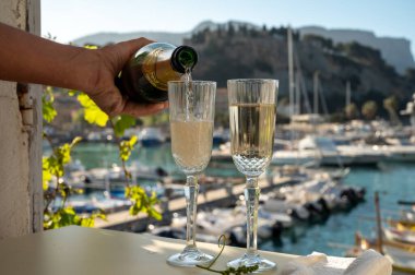 İki bardak Fransız şampanyası, köpüklü şarap ve renkli balıkçıların Cassis, Provence, Fransa 'da eski bir limandaki teknelerine manzarası, Provence' de yaz tatili.