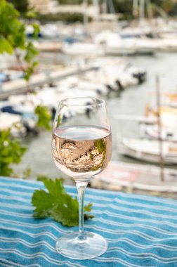 Açık terasta sunulan Rose Provencal şarabı Cassis, Provence, Fransa 'daki eski balıkçıların limanında renkli teknelerle servis ediliyor.